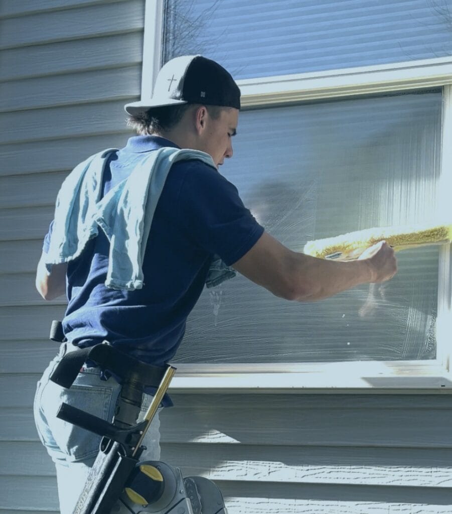 Alta Cleaning window cleaner scrubbing a window on the job