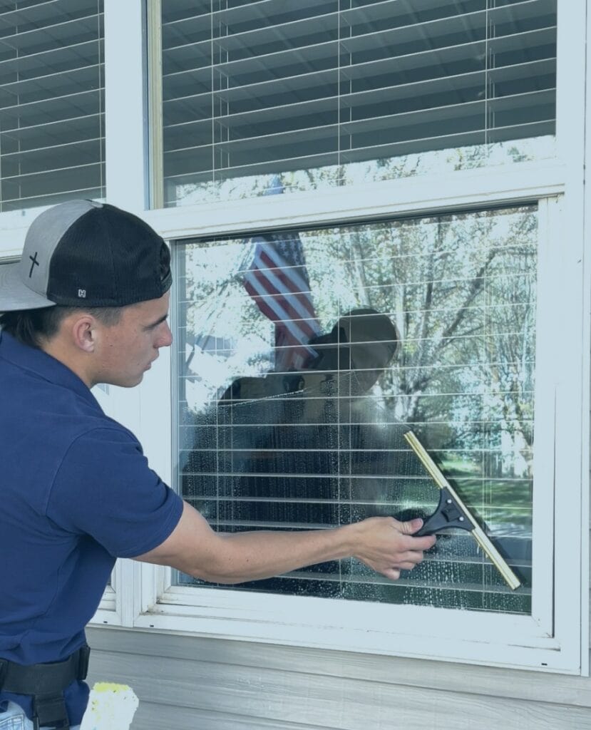 Alta Cleaning technician squeegeeing a window during a home visit