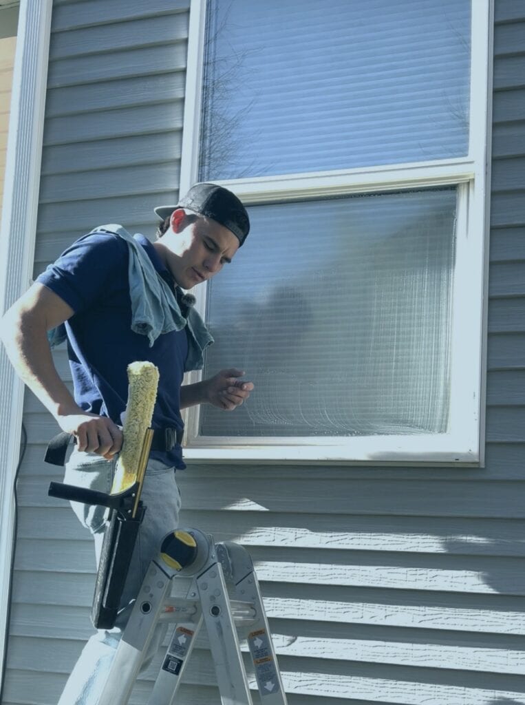Alta Cleaning technician on ladder cleaning a Utah home window